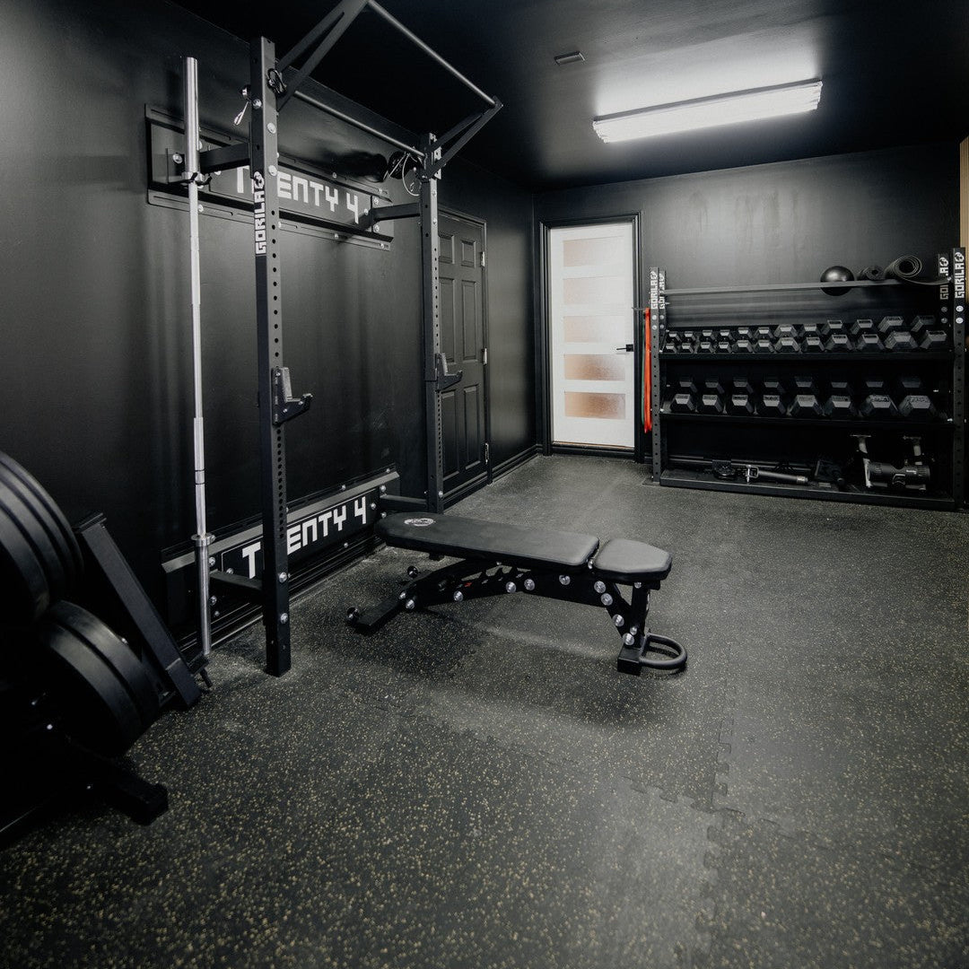 Home gym setup featuring a Gorila wallmount rack, adjustable bench, barbell, and weight plates in a modern living space, showcasing durable Canadian-made fitness equipment.