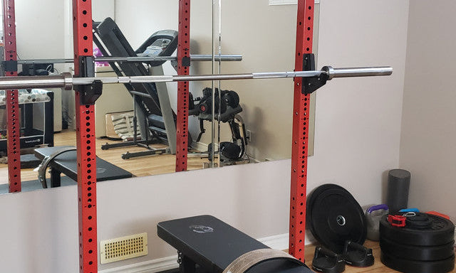 Pair of Gorila Fitness squat stands with barbell set up for squats in a compact home gym