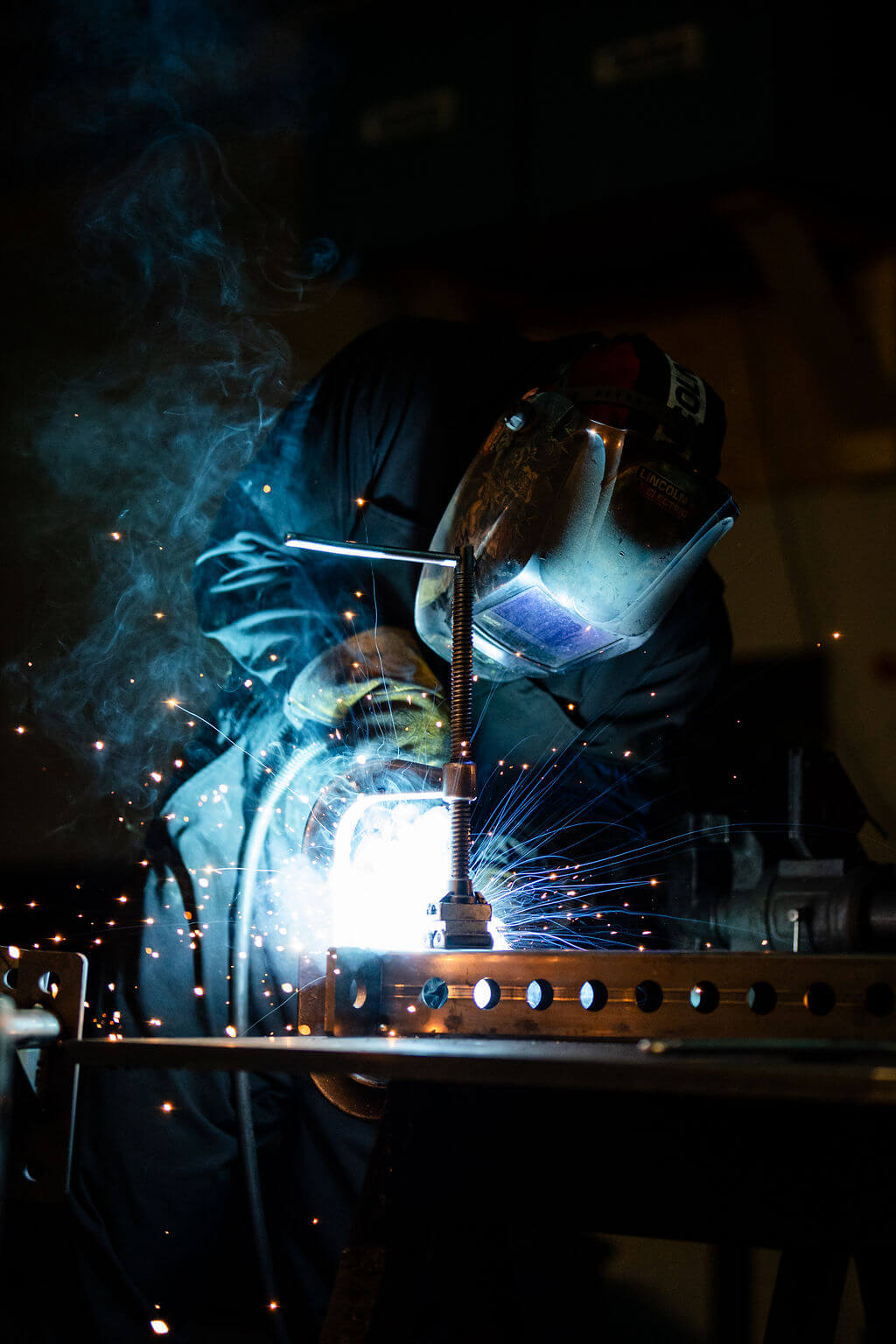 Person welding with sparks flying in a dark workshop setting