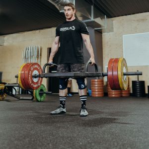 Fitness enthusiast performing deadlifts with a trap bar featuring neutral grips, allowing for a natural hand position and safer lifting technique.